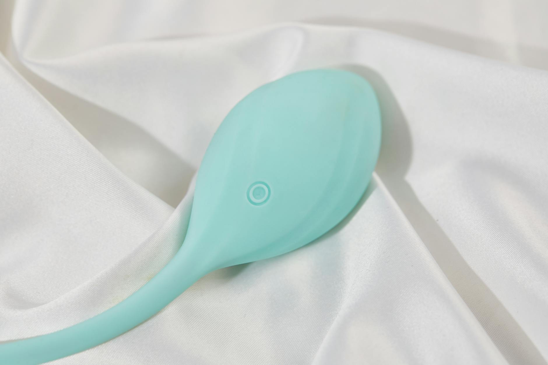 Uma mão segurando um vibrador de silicone azul contra fundo roxo, simbolizando autossuficiência e cuidado pessoal