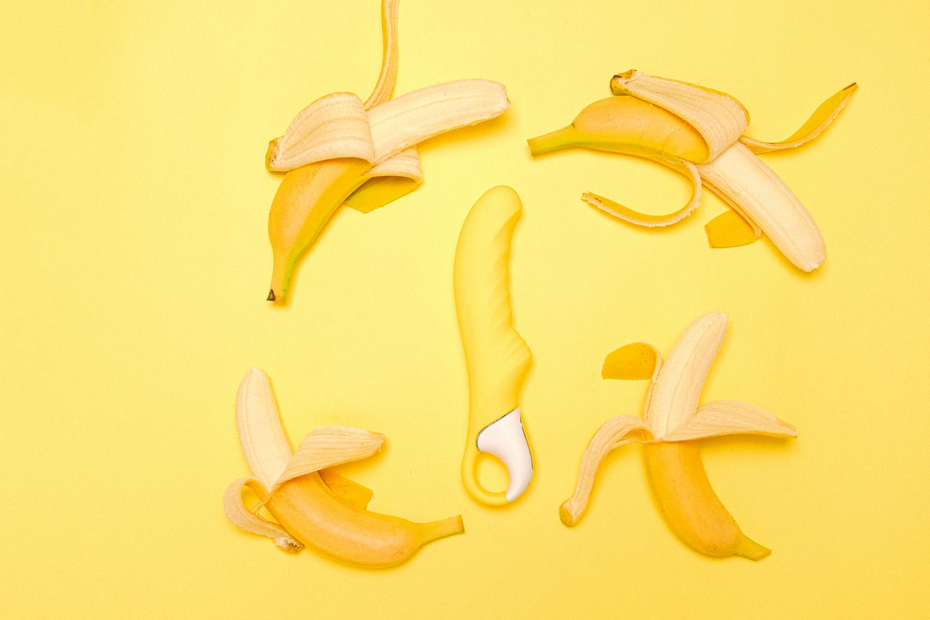 Yellow lemon clitoral vibrator surrounded by peeled lemons on a bright yellow background, symbolizing pleasure recovery.