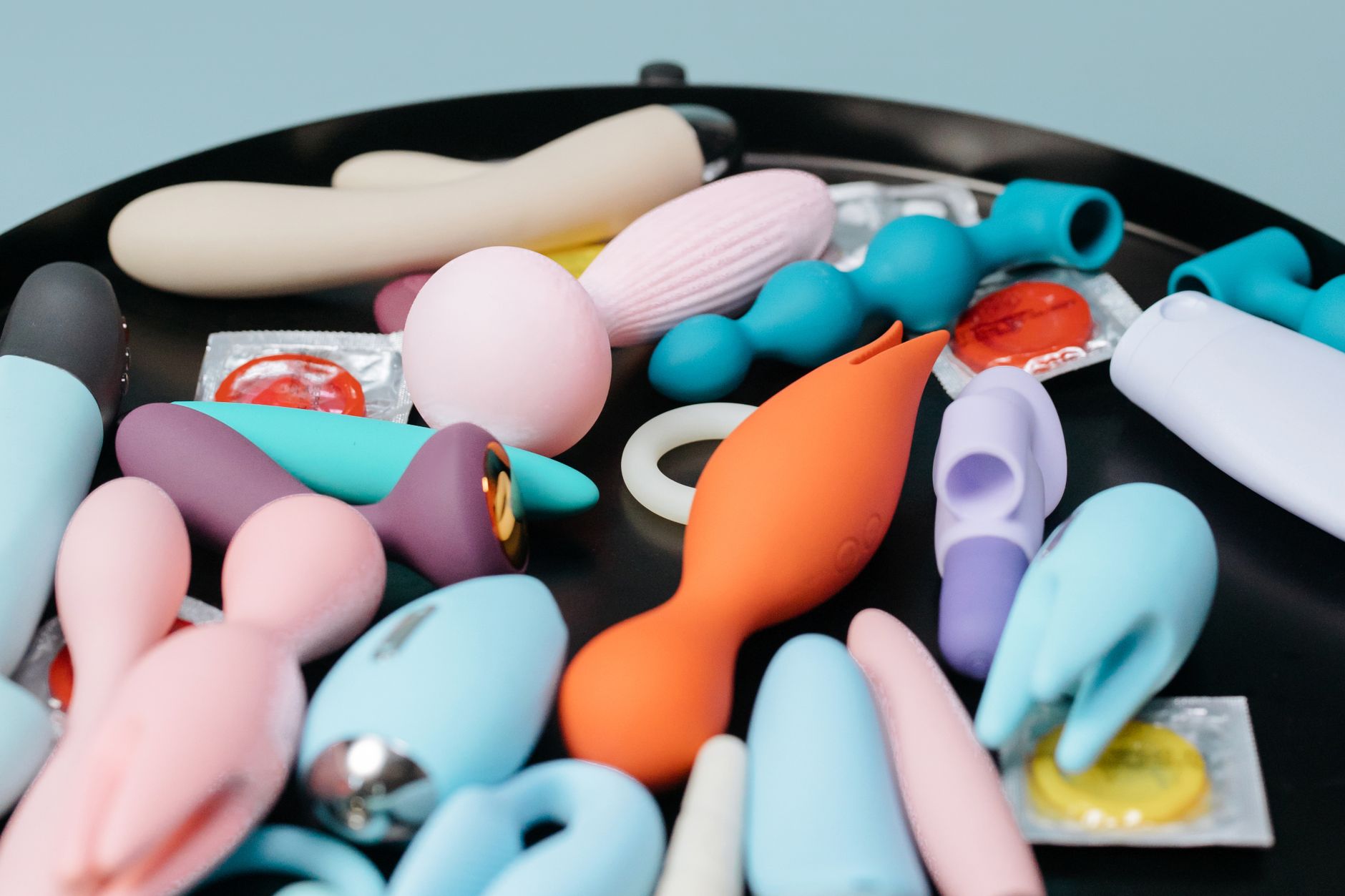 Vibrador de silicone azul na mão contra fundo roxo minimalista, promovendo amor próprio e sexualidade