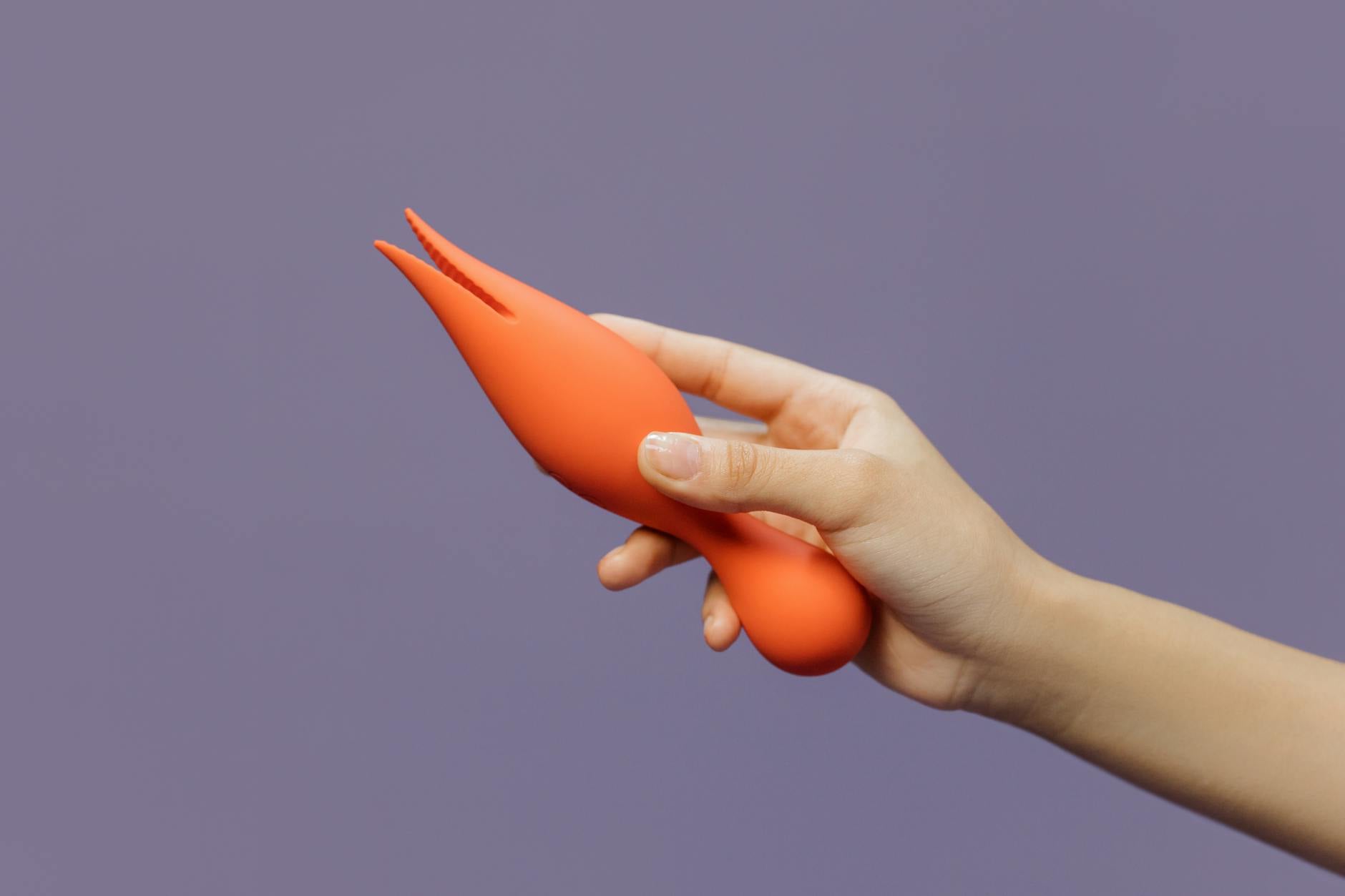 A hand holding a lemon vibrator against a purple backdrop, representing stress-free pleasure