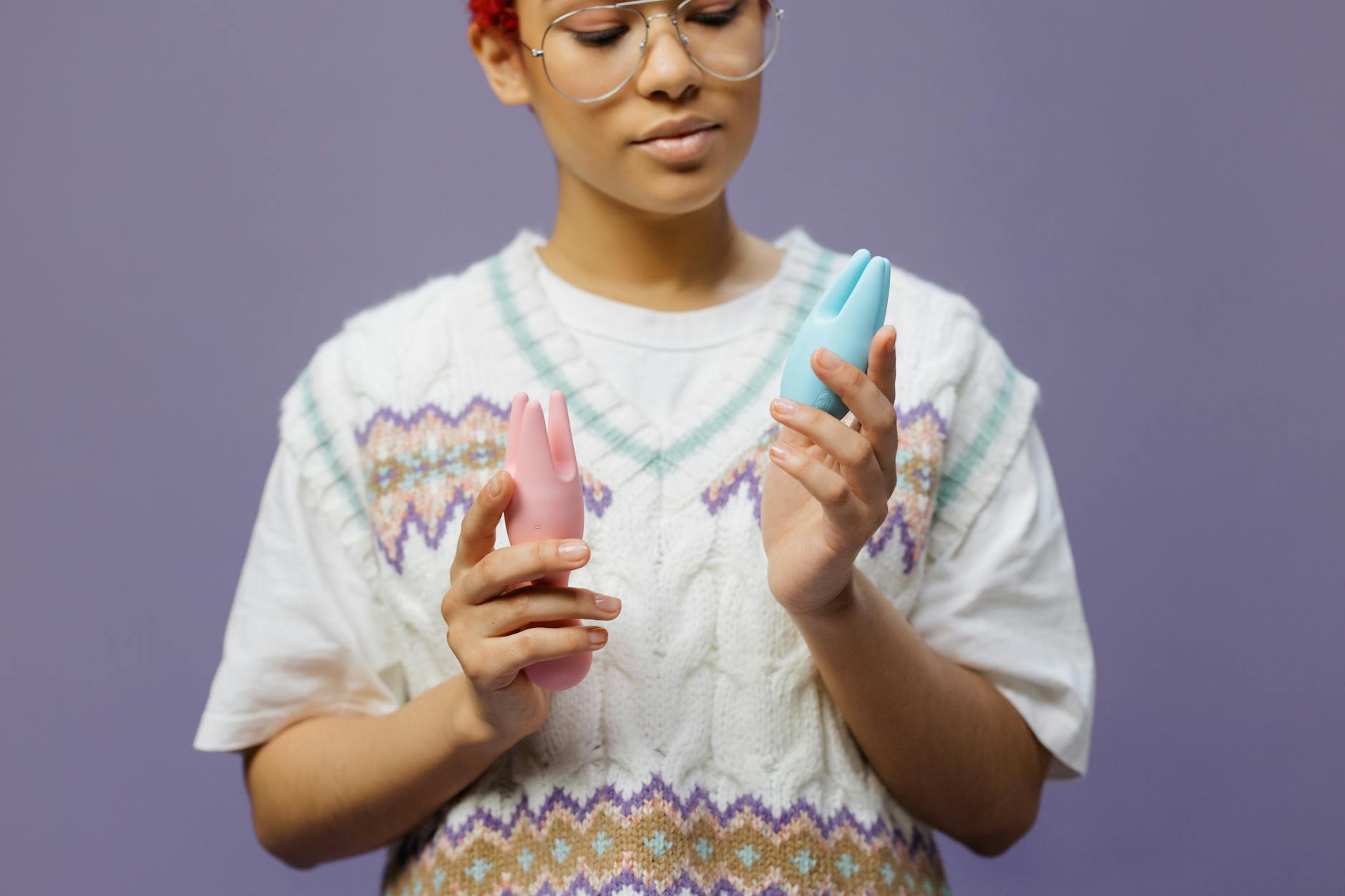 Person holding blue and pink silicone vibrators, showing varied colors of pleasure tools
