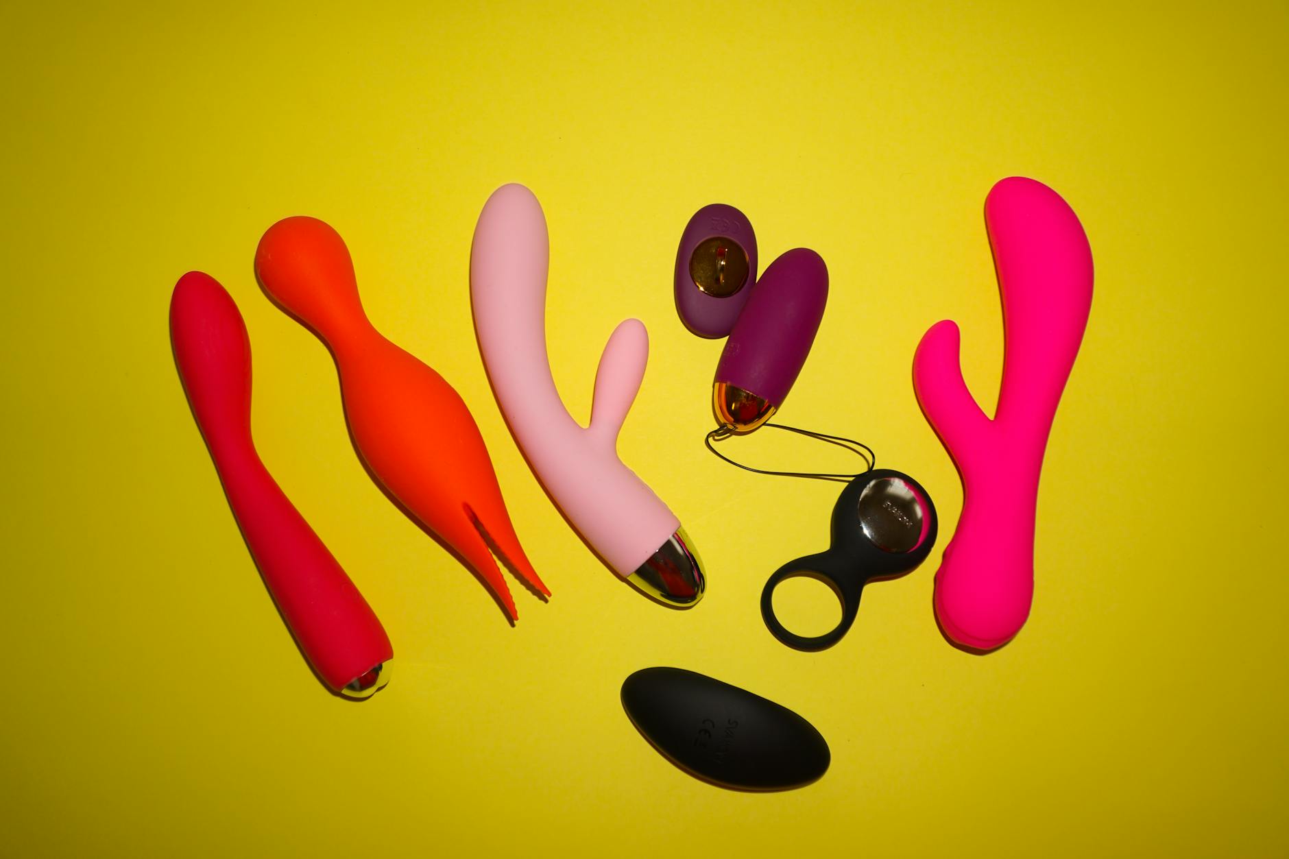 Yellow silicone lemon vibrator surrounded by fresh bananas on yellow background